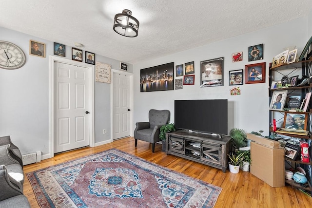 sitting room featuring wood finished floors, baseboards, baseboard heating, and a textured ceiling