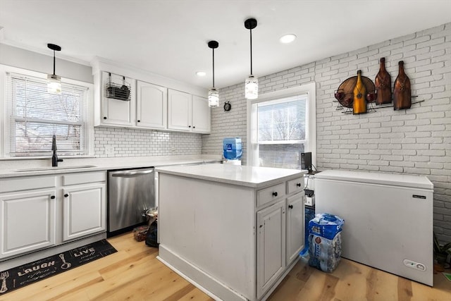 kitchen featuring a sink, light wood-style floors, brick wall, white cabinets, and dishwasher