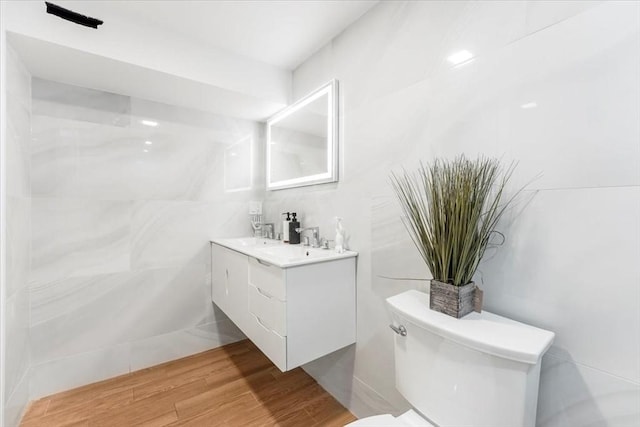 bathroom with hardwood / wood-style flooring, toilet, and vanity