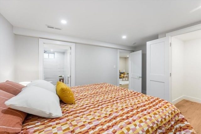 bedroom with light hardwood / wood-style flooring and ensuite bath