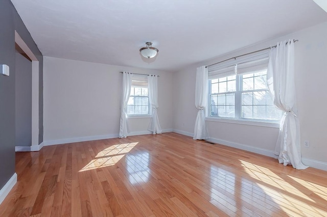 empty room featuring visible vents, light wood-style flooring, and baseboards