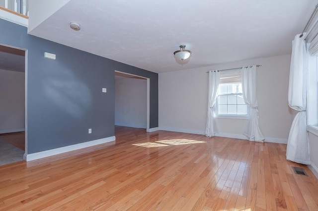 unfurnished room with baseboards, visible vents, and light wood-style floors