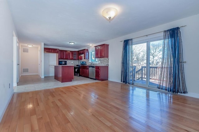 kitchen with light wood finished floors, dishwasher, open floor plan, dark brown cabinets, and backsplash