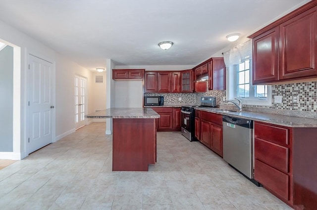 kitchen with reddish brown cabinets, tasteful backsplash, appliances with stainless steel finishes, and a sink