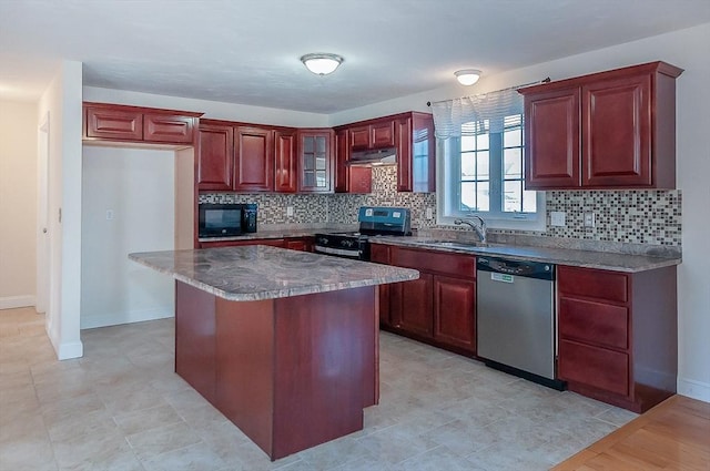 kitchen with decorative backsplash, appliances with stainless steel finishes, a sink, dark brown cabinets, and under cabinet range hood