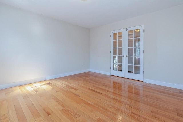 spare room featuring light wood finished floors, baseboards, and french doors