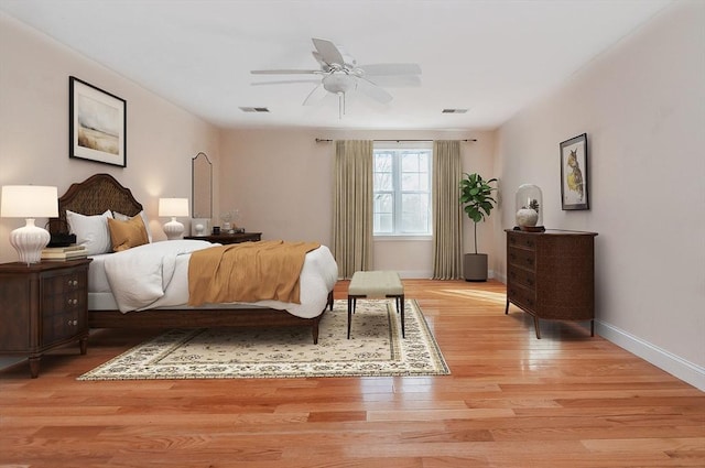 bedroom with a ceiling fan, light wood-type flooring, visible vents, and baseboards