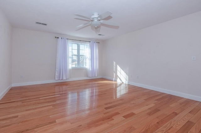 spare room with light wood-style floors, visible vents, ceiling fan, and baseboards