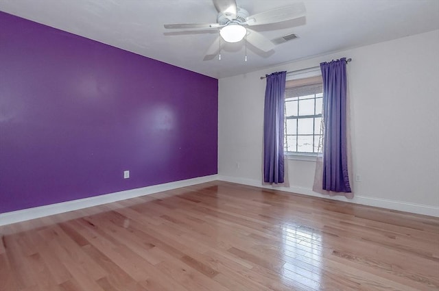 spare room featuring light wood-type flooring, baseboards, visible vents, and ceiling fan