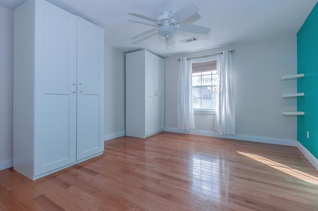 unfurnished bedroom with a ceiling fan, light wood-type flooring, visible vents, and baseboards