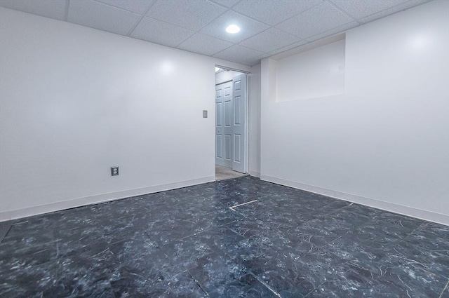 spare room with a paneled ceiling and baseboards