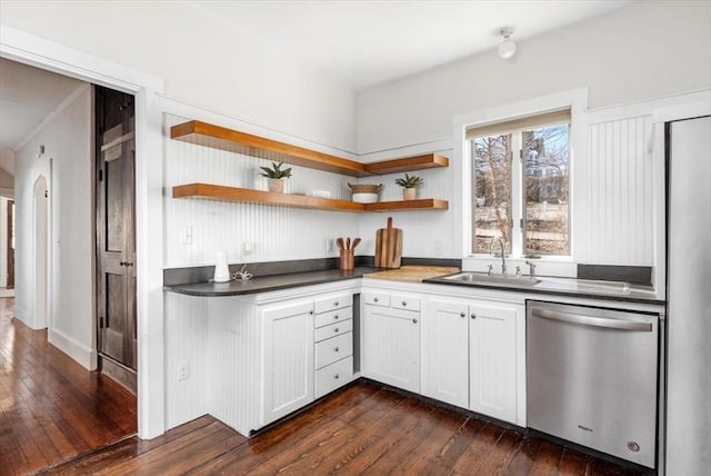 kitchen with dark wood finished floors, open shelves, arched walkways, a sink, and dishwasher