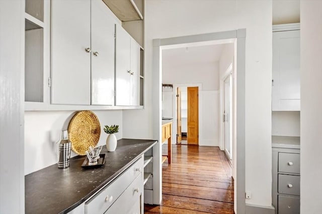 kitchen with dark wood finished floors, dark stone countertops, and white cabinetry