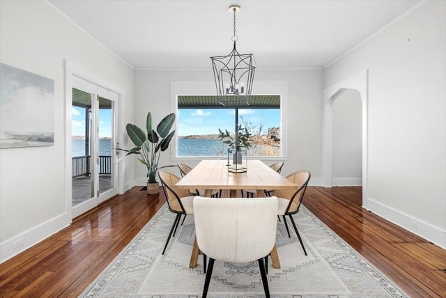 dining space featuring hardwood / wood-style floors, baseboards, and arched walkways