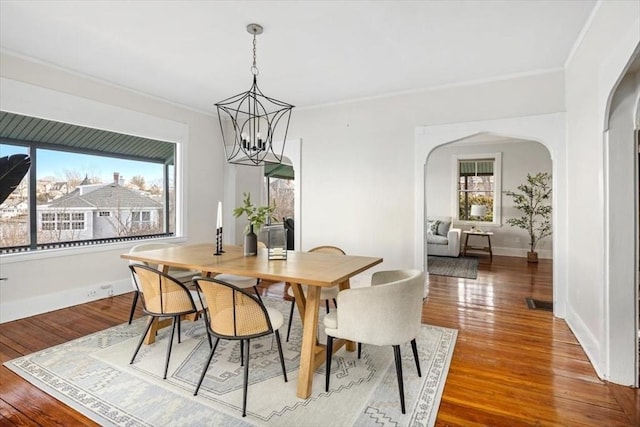 dining room featuring baseboards, arched walkways, wood-type flooring, and a chandelier