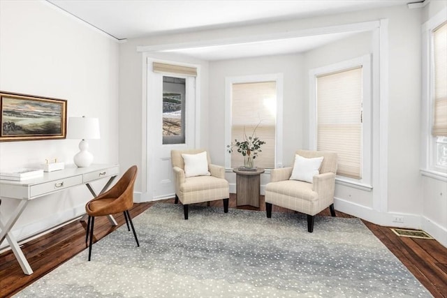 living area featuring visible vents, wood finished floors, and baseboards