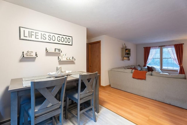 dining room featuring wood-type flooring and a baseboard heating unit