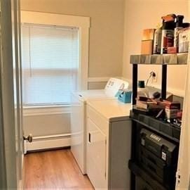 laundry room with a baseboard heating unit, washing machine and clothes dryer, and light hardwood / wood-style flooring