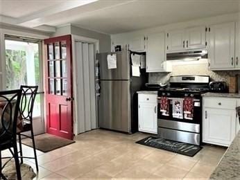 kitchen with white cabinets, decorative backsplash, light tile patterned floors, and stainless steel appliances