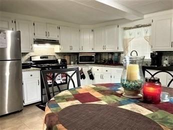 kitchen featuring light tile patterned floors, backsplash, white cabinets, and stainless steel appliances