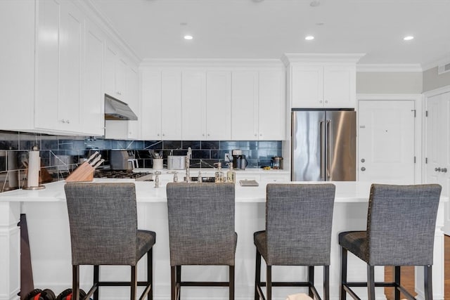 kitchen featuring white cabinetry, high end fridge, and a breakfast bar area