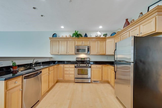 kitchen with stainless steel appliances, light brown cabinetry, light hardwood / wood-style floors, and sink