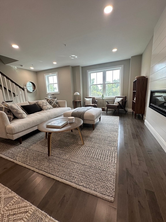 living room with a large fireplace and dark hardwood / wood-style floors