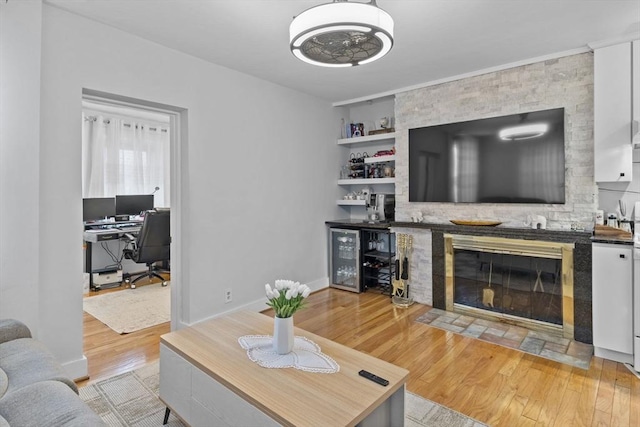 living room with built in shelves, baseboards, beverage cooler, a dry bar, and light wood-style floors
