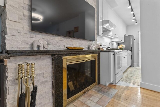 kitchen featuring track lighting, electric stove, dark countertops, light wood-style floors, and wall chimney range hood