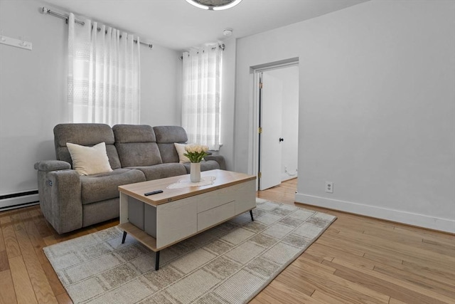 living room featuring light wood finished floors, a baseboard heating unit, and baseboards
