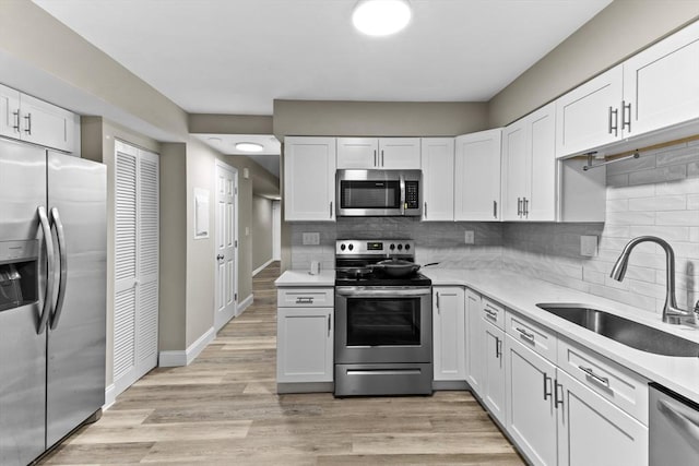 kitchen with sink, white cabinets, stainless steel appliances, and light hardwood / wood-style flooring