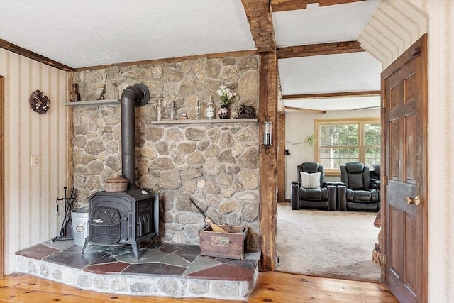 room details featuring beam ceiling, wood-type flooring, and a wood stove