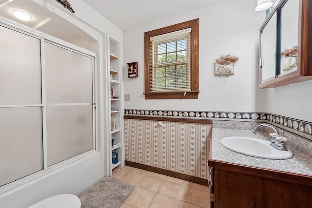 bathroom with vanity, tile patterned flooring, built in shelves, and enclosed tub / shower combo