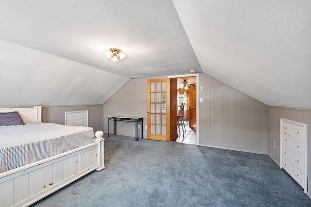 unfurnished bedroom featuring wood walls, lofted ceiling, carpet, and a textured ceiling