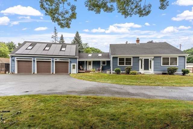 ranch-style house featuring a garage, a front lawn, and solar panels