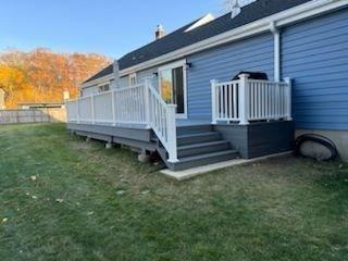 back of house with a deck and a lawn