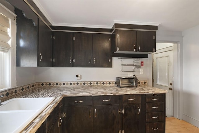 kitchen with light countertops, a toaster, a sink, light wood-style floors, and dark brown cabinets