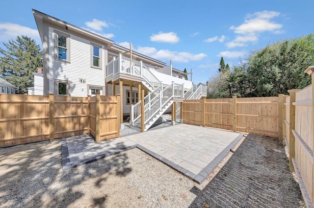 rear view of property featuring stairs, a gate, a patio area, and a fenced backyard