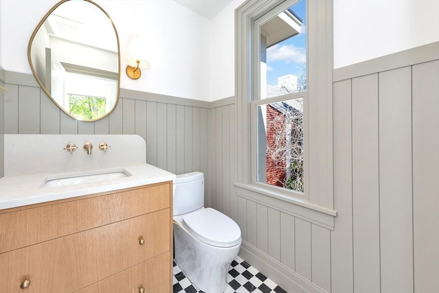 bathroom with vanity, wainscoting, tile patterned floors, and toilet