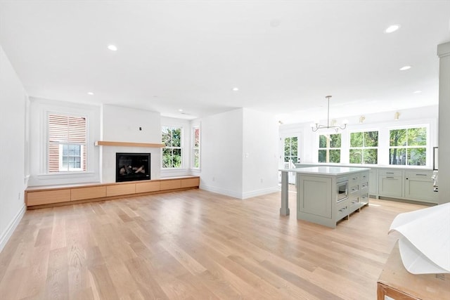 living room with baseboards, a glass covered fireplace, and light wood-style floors