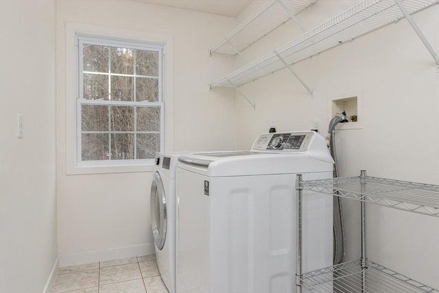 clothes washing area featuring light tile patterned floors, baseboards, washing machine and dryer, and laundry area