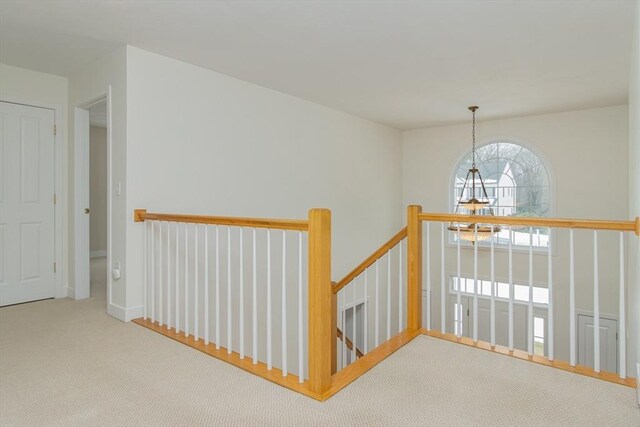 hall with an upstairs landing and carpet flooring