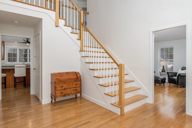 stairs with ceiling fan, baseboards, and wood finished floors