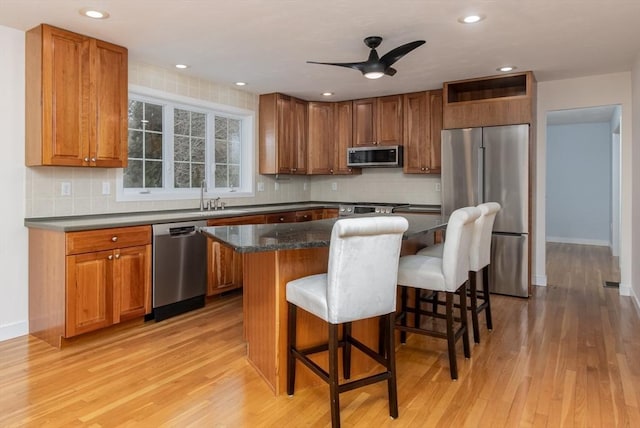 kitchen with light wood finished floors, brown cabinets, appliances with stainless steel finishes, and a kitchen island