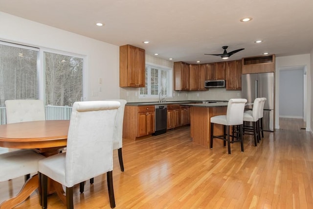 kitchen with a breakfast bar area, light wood-style flooring, a sink, stainless steel appliances, and a center island