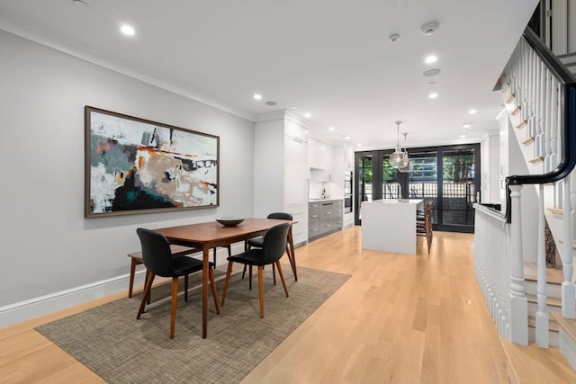 dining space with crown molding and light hardwood / wood-style flooring