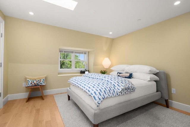 bedroom with a skylight and light hardwood / wood-style floors