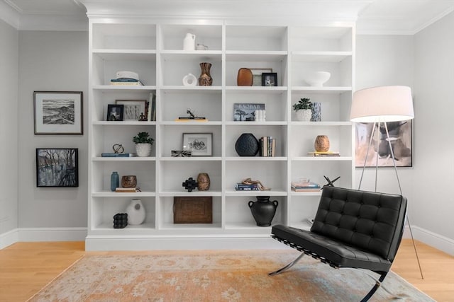 living area featuring crown molding, built in shelves, and light wood-type flooring