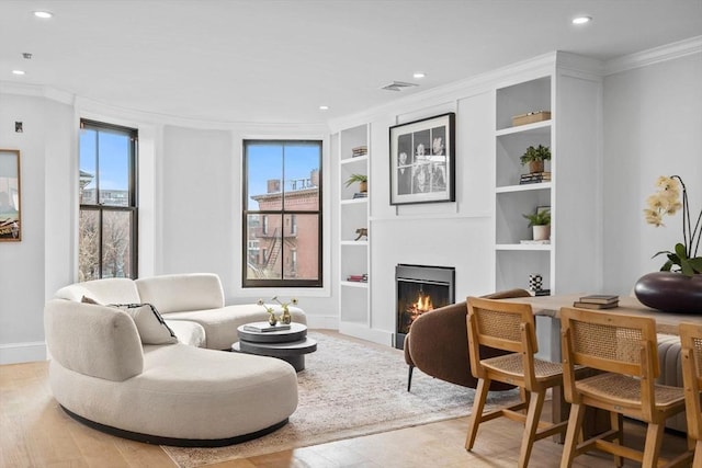 living room featuring built in shelves and crown molding