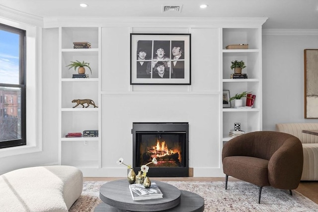 sitting room with light wood-type flooring, built in features, and ornamental molding